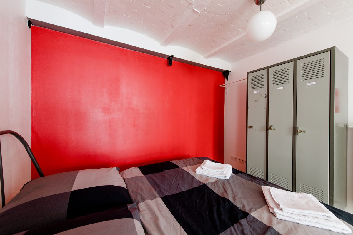 Schlafzimmer mit Spinden und roter Akzentwand