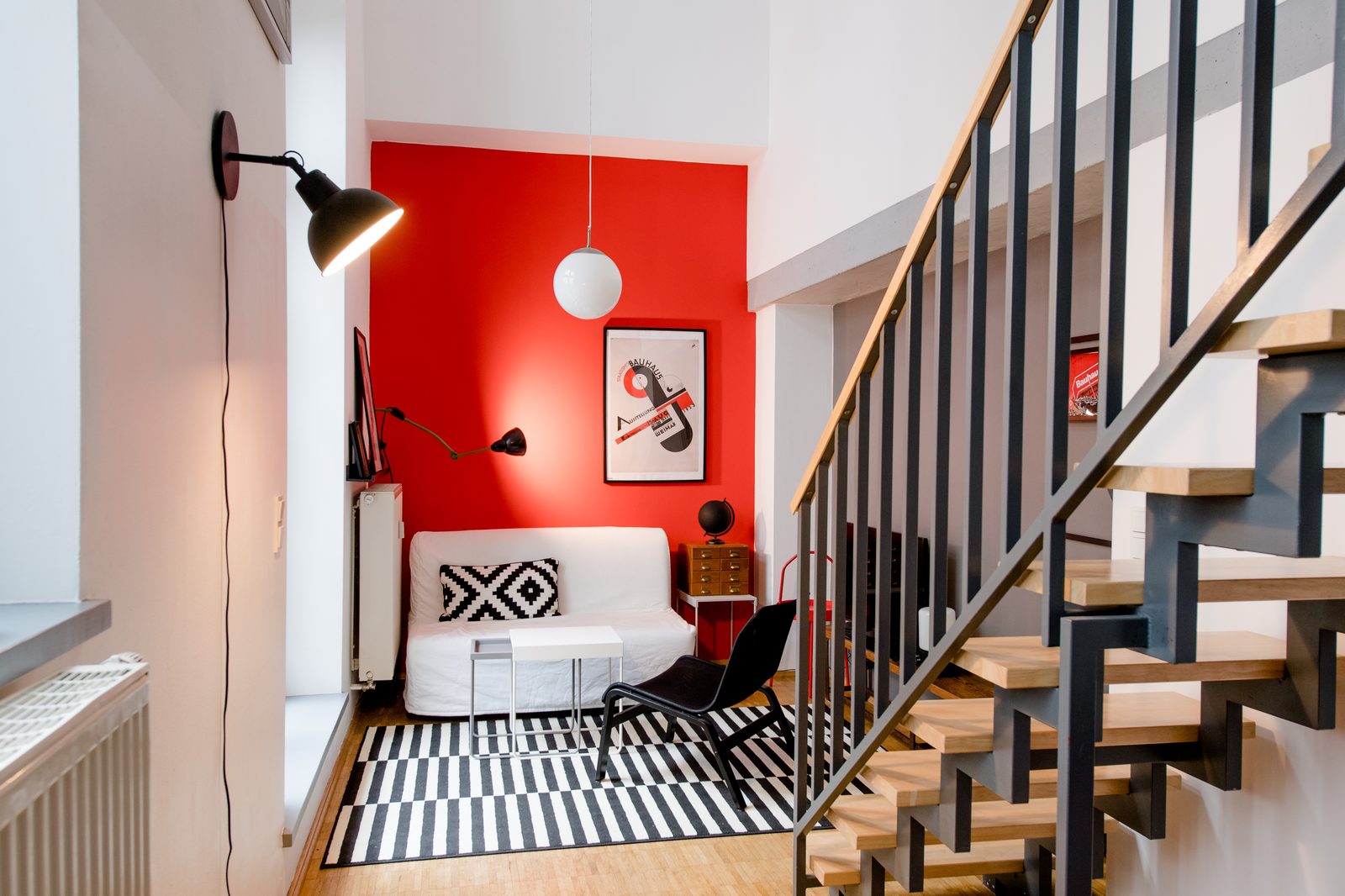 Wohnbereich von Wohnung 2 mit roter Akzentwand und Bauhaus-Poster